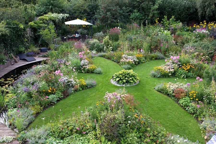 Ingrid heeft een symmetrische tuin door de mandalavorm, maar de bloemen en planten maken het heel vrolijk en speels – Tuinieren met Buitenleven